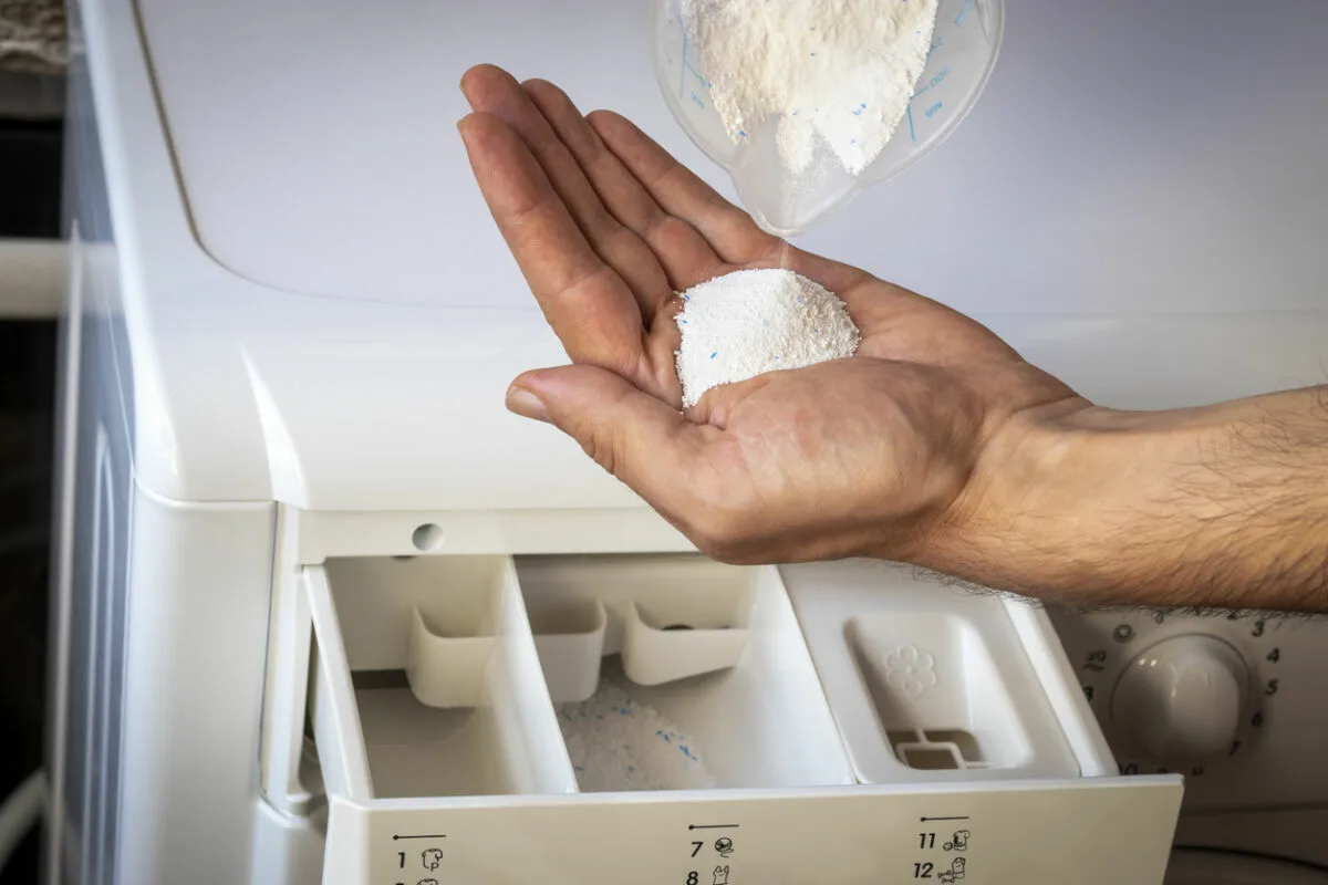 voegt wasmiddel toe aan de wasmachine